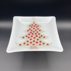 a white plate with a red and green christmas tree design on the front, sitting on a gray surface