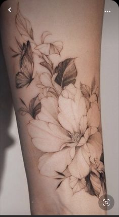 a woman's arm with flowers on it and butterflies flying around the flower tattoo