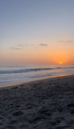 the sun is setting over the ocean at the beach