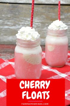 two mason jars with whipped cream and strawberries in them on a red checkered table cloth