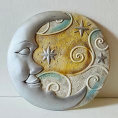 a ceramic moon and star decoration on a white wall with the moon in the sky