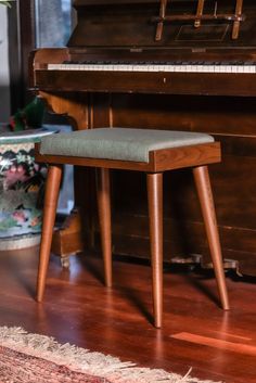 a wooden bench sitting in front of a piano on top of a hard wood floor