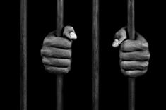 two hands holding bars in the middle of a black and white photo on a dark background