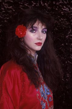 a woman with long hair wearing a red dress and flower in her hair