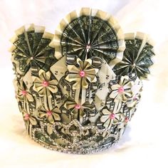 a crown made out of dollar bills with pink bows on the sides and white background