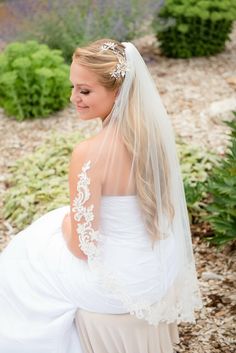 a woman in a wedding dress sitting on the ground with her veil over her head