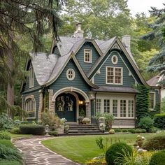 a blue house in the middle of a lush green yard with lots of trees and bushes