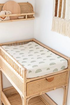 a wicker crib with a green sheet on it and shelves above the crib