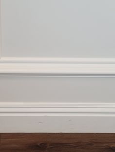 a white door handle on the side of a wooden floor in front of a wall