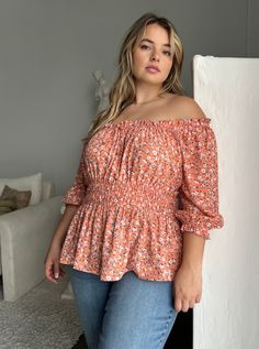 The fun and flattering Plus Size Elasticized Floral Blouse is a great addition to any warm-weather outfit collection. This plus size top is great worn with a cute pair of trending jeans for an effortless look or dress it up a bit with some statement pants. This blouse features an elasticized top hemline that can be worn on or off the shoulder, a decorative tie on the bust, and elastic around the waistline and at the ends of the 3/4 length sleeves. The material is a non-stretchy woven. This top i Orange Relaxed Fit Blouse For Vacation, Orange Floral Print Relaxed Fit Blouse, Orange Relaxed Fit Blouse With Floral Print, Relaxed Fit Orange Blouse With Floral Print, Peach Blouse For Spring Beach Occasions, Peach Blouse For Beach In Spring, Peach Blouse For Beach, Spring Season, Flowy Orange Blouse For Summer, Flowy Orange Summer Blouse