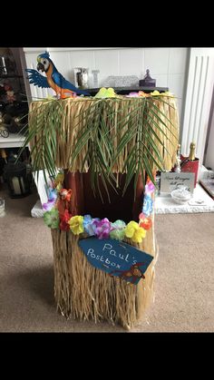 a tiki hut made out of grass with flowers and palm leaves on the roof