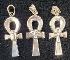 three silver colored pendants with an egyptian cross and an ani symbol on them