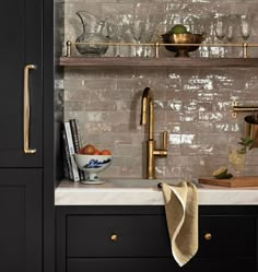 a kitchen with black cabinets and gold faucets on the countertop, along with glassware