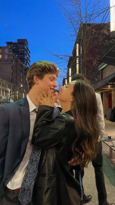 a man and woman kissing each other on the street