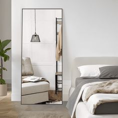 a bedroom with a bed, chair and mirror in the corner that is next to a plant