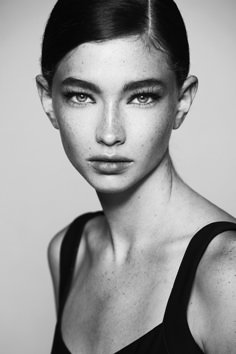 a black and white photo of a woman with freckles on her face, looking at the camera