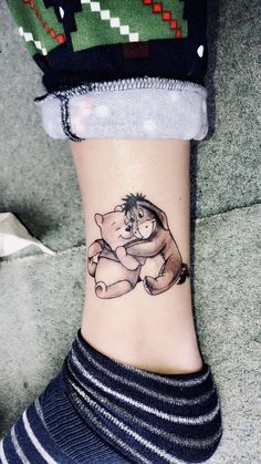 a person with a tattoo on their foot holding a teddy bear and hugging it's face