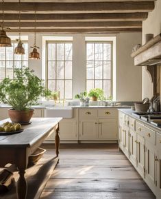 a kitchen with white cabinets and wooden floors, an island table in front of the window