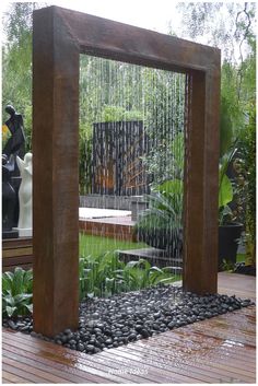 an outdoor fountain in the middle of a garden with rocks and water flowing from it