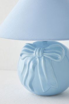 a blue vase with a bow on it and a white lamp in the corner behind it