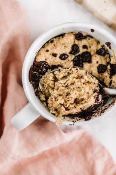 two spoons are in a mug filled with oatmeal and chocolate chips