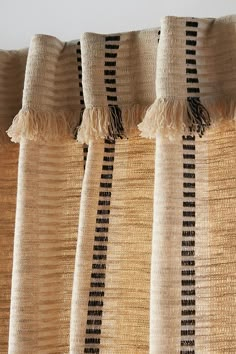 the curtains are lined up with black and white striped fabric on them, along with tassels