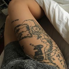 a woman laying in bed with her legs crossed and tattoos on her leg are shown