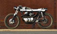 a black and white motorcycle parked in front of a brick wall