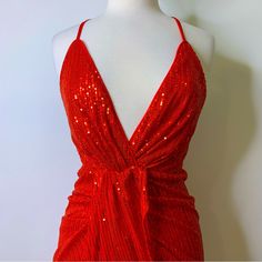 a red dress with sequins on it sitting on a mannequin