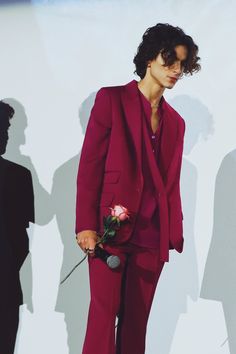 a man in a red suit holding a rose