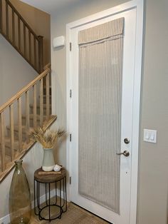 a white door and some vases on a table in front of a stair case