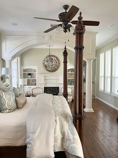 a large bed sitting in a bedroom next to a fireplace under a ceiling fan on top of a hard wood floor