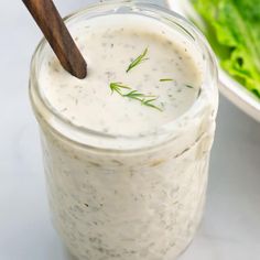 a jar filled with dressing next to a salad