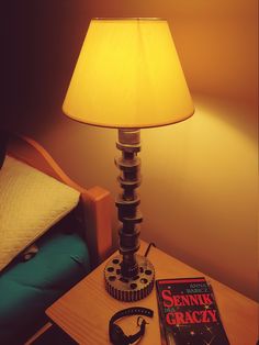 a lamp sitting on top of a wooden table next to a book and headphones