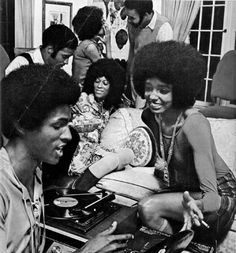 a group of people sitting around each other in a living room with an old record player