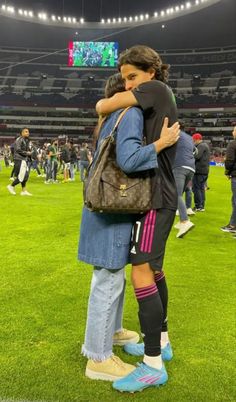 two people hugging each other on the field at a football game in an empty stadium