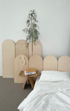 a bed with white sheets and pillows next to a wooden headboard on the wall