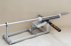 a machine that is sitting on top of a white surface with a wooden handle and two metal bars