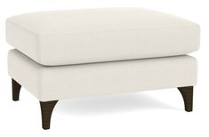 a white ottoman sitting on top of a wooden frame with legs and an upholstered cushion