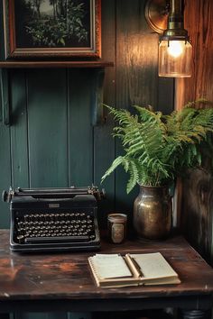 an old fashioned typewriter sitting on top of a table next to a potted plant