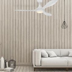 a white couch sitting in front of a wooden wall with a ceiling fan above it