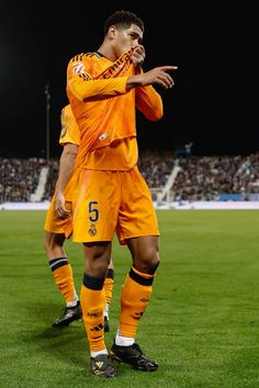 a soccer player is standing on the field with his hands together and pointing at something