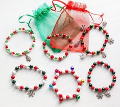 four bracelets with beads and charms on them sitting next to a drawsack bag