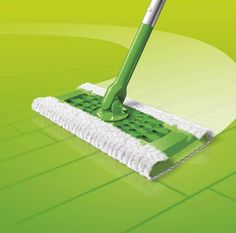 a mop with a green handle on top of a tiled floor in front of a white circle