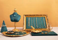 an assortment of jewelry on display in front of a gold framed mirror and other items