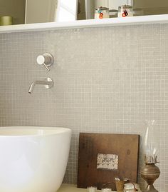 a bath room with a large white tub next to a sink and a mirror on the wall