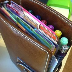 a leather wallet with pens, pencils and markers in it sitting on a table