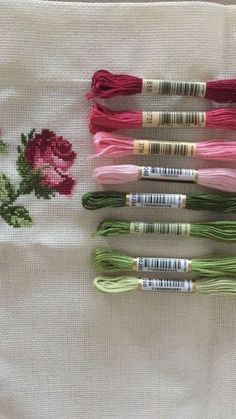 four spools of thread sitting next to each other on a white cloth with pink flowers