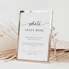 a wedding guest book sitting on top of a table next to palm fronds