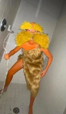 a woman in a costume is standing on the shower head and holding a plunger